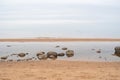 Sandy beach of  Baltic sea covered with big stones on cloudy spring morning. Royalty Free Stock Photo