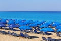 Sandy beach with blue parasols and sunbeds