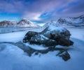 Sandy beach with blue sea reflected in water and rocks in snow Royalty Free Stock Photo