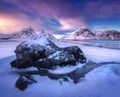 Sandy beach with blue sea reflected in water and rocks in snow Royalty Free Stock Photo