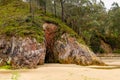 Sandy beach with a cave entrance into a rock. Royalty Free Stock Photo