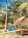 A sandy beach with coconut palms and bamboo huts is adorned with a few tents. Royalty Free Stock Photo