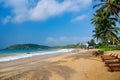 Sandy beach with deckchairs under the coconut trees