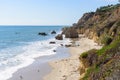 Sandy beach at the foot of a rugged cliff ag the coast of California