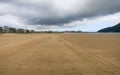 Sandy beach with footprints and houses in the background.