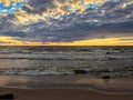 Sandy beach with grey sea waves on stormy Gulf of Finland, sunset sky