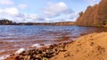 Sandy beach by the lake with autumn forest around. Sunny day and colorful trees. Autumn landscape Royalty Free Stock Photo