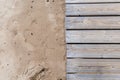 .a sandy beach on the left with footprints and a wooden boardwalk next to it on the right Royalty Free Stock Photo