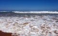 Sandy beach with long waves and white foam on the southern coast of the ocean Royalty Free Stock Photo