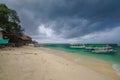 Sandy beach with moored Indonesian boats on the tropical island of Gili Meno. Heavy leaden clouds hung over the beach, a