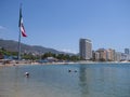 Sandy beach panorama at bay of ACAPULCO city in Mexico with luxury hotels buildings and mexican flag Royalty Free Stock Photo