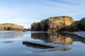 Sandy beach panorama with tidal pools and jagged broken cliffs behind in warm evening light Royalty Free Stock Photo