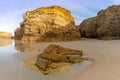 Sandy beach panorama with tidal pools and jagged broken cliffs behind in warm evening light Royalty Free Stock Photo