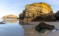 Sandy beach panorama with tidal pools and jagged broken cliffs behind in warm evening light Royalty Free Stock Photo