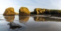 Sandy beach panorama with tidal pools and jagged broken cliffs behind in warm evening light Royalty Free Stock Photo