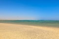 Sandy beach on the Red Sea in Egypt. Turquoise blue water. Calm sea level above the coral bedrock. Sunny day with blue sky without Royalty Free Stock Photo