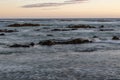 Sandy beach, with rocky outcroppings at the shoreline at sunset in Franzkraal, South Africa