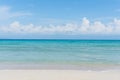 Sandy beach with rolling calm wave of ocean on sunny day on background white clouds in blue sky