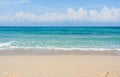 Sandy beach with rolling calm wave of ocean on sunny day on background white clouds in blue sky