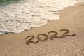 Sandy beach, sea wave and the inscription 2022.