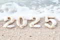 Sandy beach with seashells forming the number 2025 washed by ocean waves Royalty Free Stock Photo