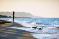 Sandy beach shoreline with seagulls drinking water at sunset. Beautiful sea landscape with breaking waves and woman on background Royalty Free Stock Photo