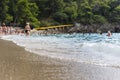 Sandy beach with spalshing waves and people swimming and enjoying summer Royalty Free Stock Photo