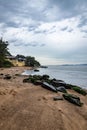 Sandy beach with stones by the water under gray cloudy sky at sunset, vertical shot Royalty Free Stock Photo