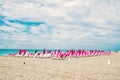 Sandy beach with sunbeds and folded, pink umbrellas