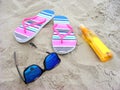 Sandy beach with sunglasses, flip-flops and suncare milk Royalty Free Stock Photo