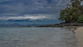 Sandy beach of a tropical island. Exposed rocks of the seabed are visible