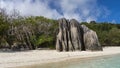 On the sandy beach of a tropical island, among lush vegetation, picturesque granite rocks rise.