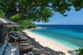 Sandy beach with turquoise water and lounge chairs under shade of tropical trees Royalty Free Stock Photo