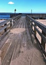 Sandy boardwalk leading to beach and pier.
