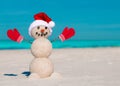 Sandy Christmas snowman in red Santa hat and mittens without sunglasses. Beach Snowman. Royalty Free Stock Photo