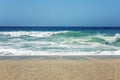 Sandy coast of the turquoise sea. Surging waves, sunny windy day. Space for text Royalty Free Stock Photo