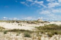 Sandy dunes overgrown by clumps of grass and blue sky with white clouds in sunny summer day. Lacka dune Near Leba.