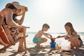 Sandy fun under the summer sun. an adorable little boy and girl playing with beach toys in the sand while their mother Royalty Free Stock Photo