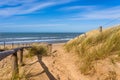 Sandy path over a dune with a fence in the sun Royalty Free Stock Photo