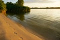 Sandy riverbank with footprints in the sand and calm river waters at sunset Royalty Free Stock Photo
