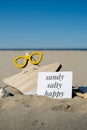 SANDY SALTY HAPPY text on paper greeting card on background of funny starfish in glasses summer vacation decor. Beach Royalty Free Stock Photo