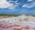 sandy sea beach with waves under a cloudy sky Royalty Free Stock Photo