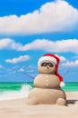 Sandy snowman in red Santa hat and sunglasses at tropical ocean beach Royalty Free Stock Photo