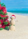 Sandy Snowman in Santa hat under decorated Christmas Tree at beach Royalty Free Stock Photo