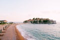 Sandy spit with sun loungers near the isthmus of the island of Sveti Stefan. Montenegro