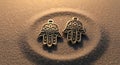 Two Hamsa hand pendants, made of intricately detailed metal, rest on a textured Royalty Free Stock Photo