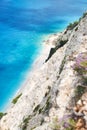 Sandy wild beach with clear water and wild thyme at the edge of the cliff