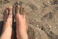 Sandy woman feet on the beach and brown sand with little rocks Royalty Free Stock Photo