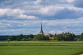 Sanga Church in the distance of a green meadow under a cloudy blue sky Royalty Free Stock Photo