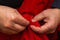 Sanior old man or woman Sews with a needle and thread at home. Fingers hands of the seamstress is using a needle and red thread to Royalty Free Stock Photo